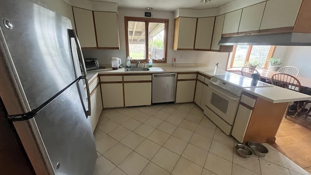 kitchen featuring light countertops, a peninsula, appliances with stainless steel finishes, and light tile patterned floors