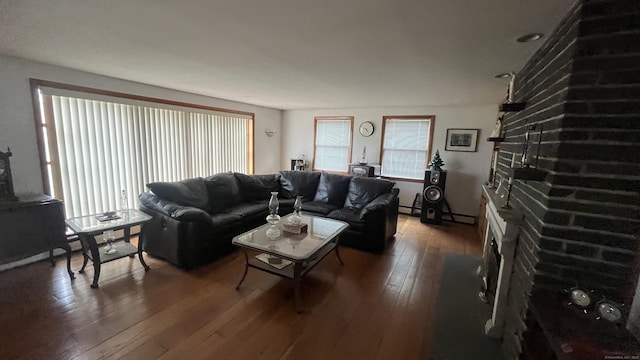 living area with a baseboard radiator, hardwood / wood-style floors, and a brick fireplace