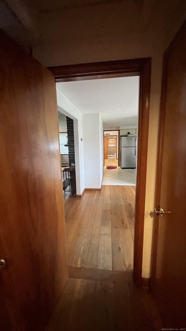 hallway featuring wood-type flooring and baseboards