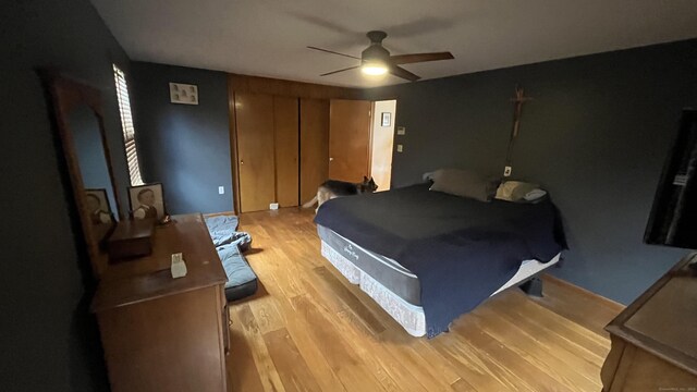 bedroom with a ceiling fan, light wood-style floors, and a closet
