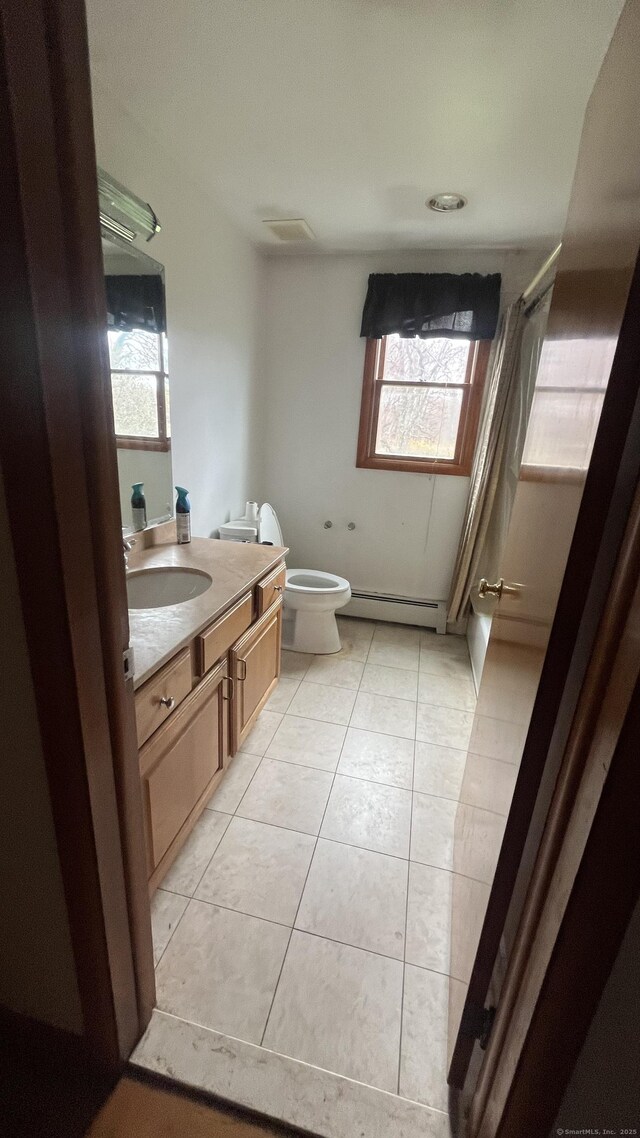 bathroom featuring tile patterned floors, baseboard heating, vanity, and plenty of natural light