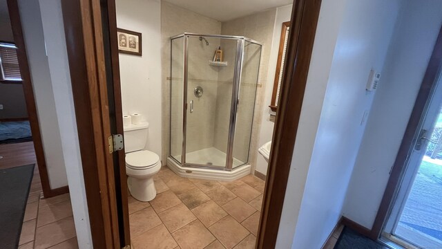 full bath with tile patterned flooring, a shower stall, and toilet