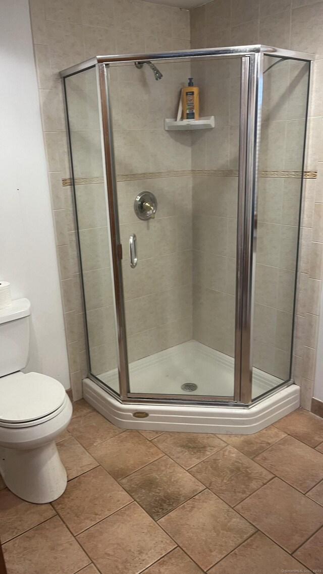 bathroom featuring toilet and a stall shower