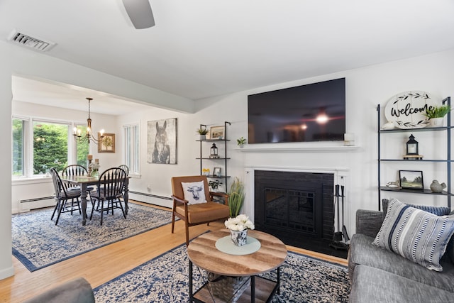 52 Pine Orchard Rd, Branford, CT 06405 - living room featuring wood finished floors, baseboard heating, a chandelier, a fireplace with flush hearth, and baseboards