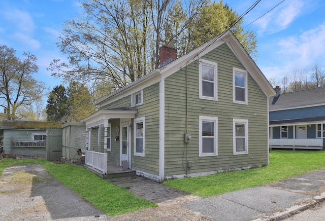 traditional-style home with a chimney and a front lawn