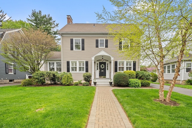 colonial house with a front lawn and a chimney