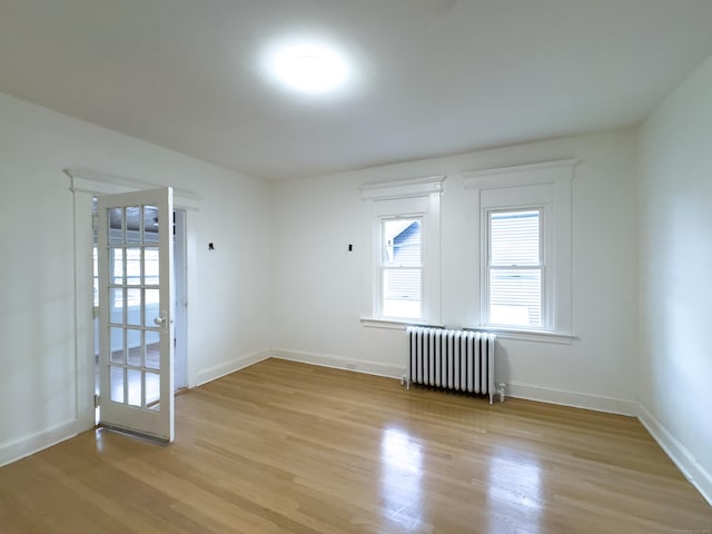 spare room with radiator, baseboards, and light wood-style floors