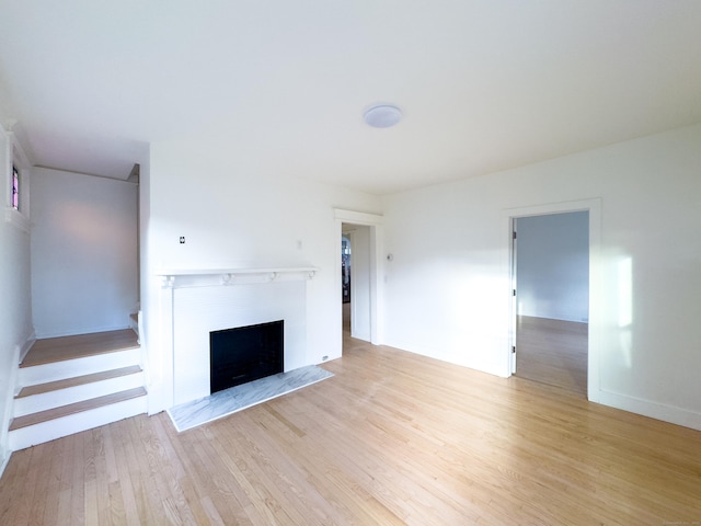 unfurnished living room with light wood-type flooring, baseboards, and a fireplace