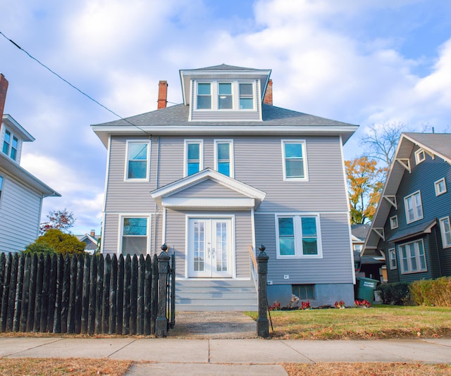 traditional style home with a chimney, a front lawn, fence, and french doors