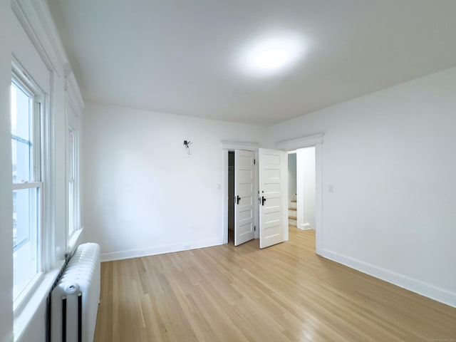 spare room with radiator, baseboards, and light wood finished floors