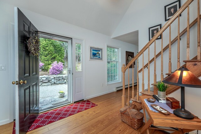 foyer featuring plenty of natural light, light wood-style flooring, baseboard heating, and stairs