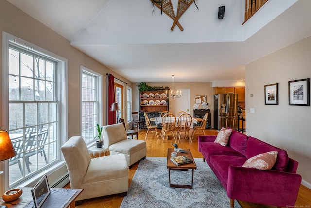 living area with a notable chandelier, a baseboard radiator, and light wood-type flooring