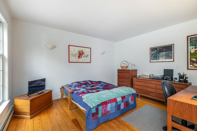 bedroom with a baseboard radiator and light wood-style floors
