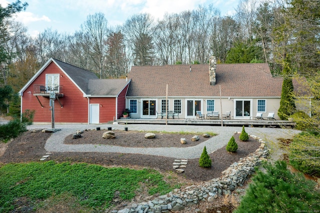 back of property with a deck, a chimney, and roof with shingles