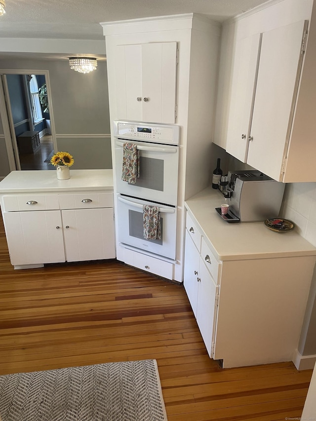 386 Bloomfield Ave, West Hartford, CT 06117 - kitchen with white cabinets, hardwood / wood-style flooring, light countertops, and double oven