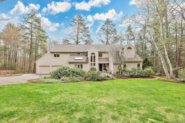 view of front of house featuring a chimney, a garage, driveway, roof with shingles, and a front lawn