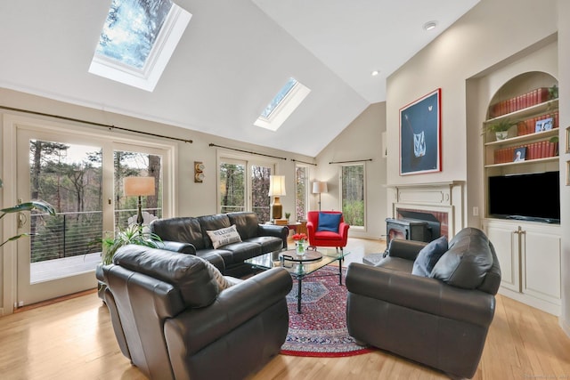 living room with a brick fireplace, light wood finished floors, and vaulted ceiling with skylight