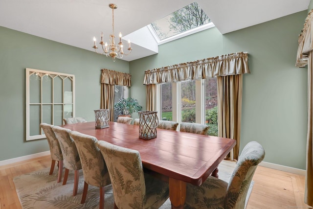 dining space featuring light wood finished floors, a notable chandelier, and baseboards