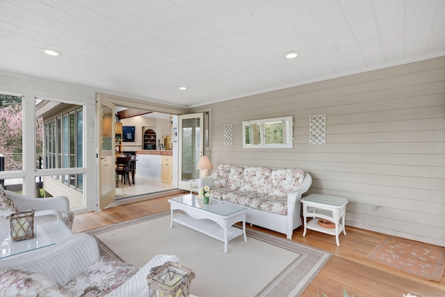 living area featuring wooden walls, recessed lighting, and light wood-style floors