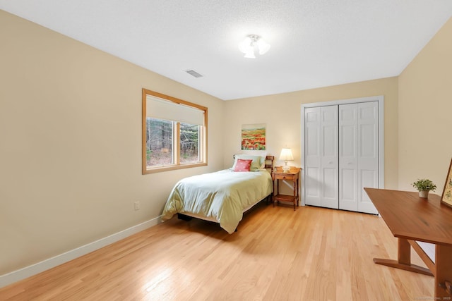bedroom with a closet, visible vents, baseboards, and light wood-type flooring