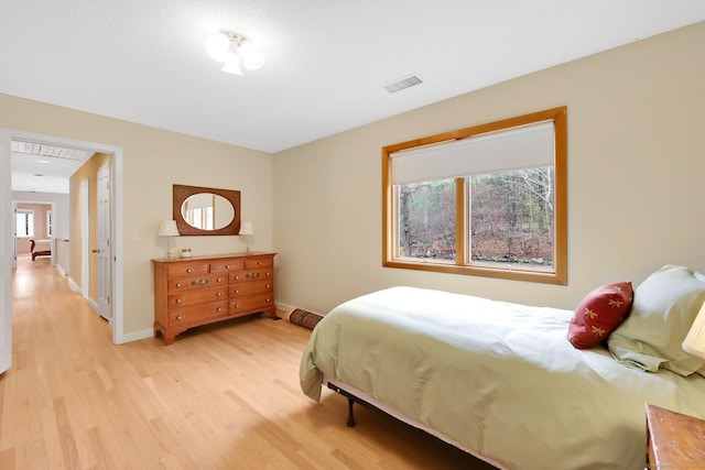 bedroom featuring visible vents, light wood-style flooring, multiple windows, and baseboards