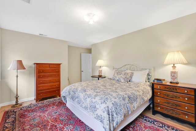 bedroom featuring wood finished floors, visible vents, and baseboards
