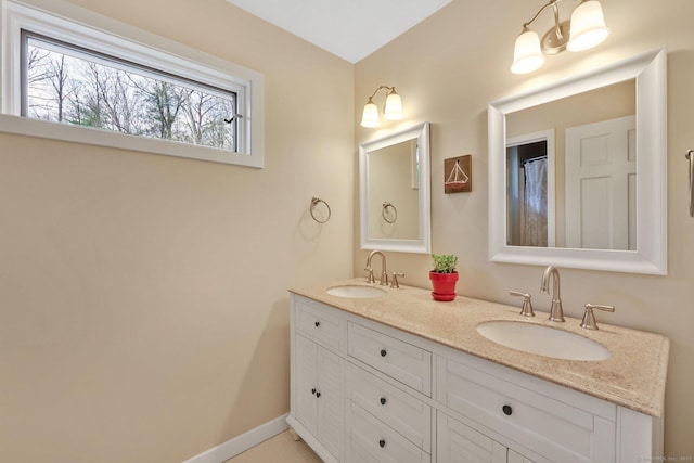 full bathroom featuring double vanity, baseboards, and a sink