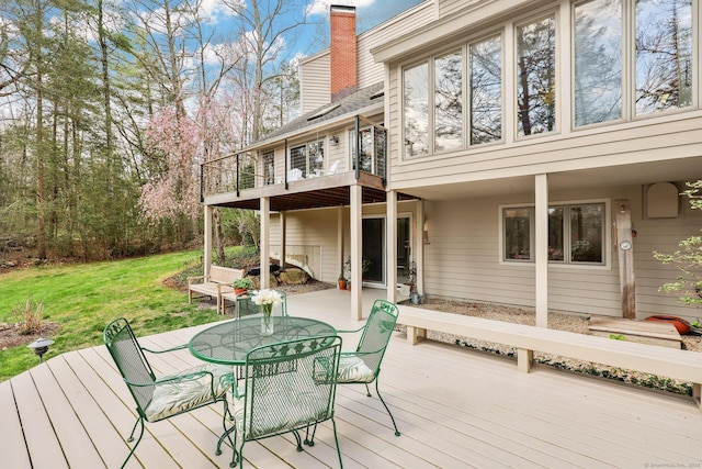 wooden terrace featuring a lawn and outdoor dining space