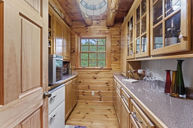kitchen with light wood-style flooring, beam ceiling, glass insert cabinets, wood walls, and wooden ceiling