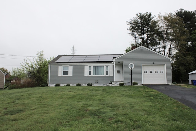 ranch-style home featuring a front lawn, aphalt driveway, solar panels, and a garage