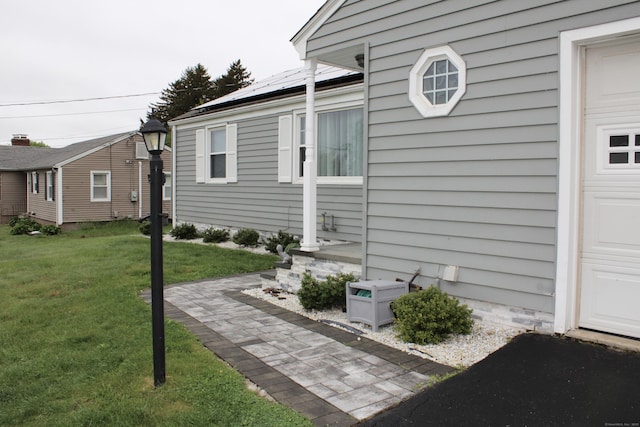 view of side of home with a yard and roof mounted solar panels