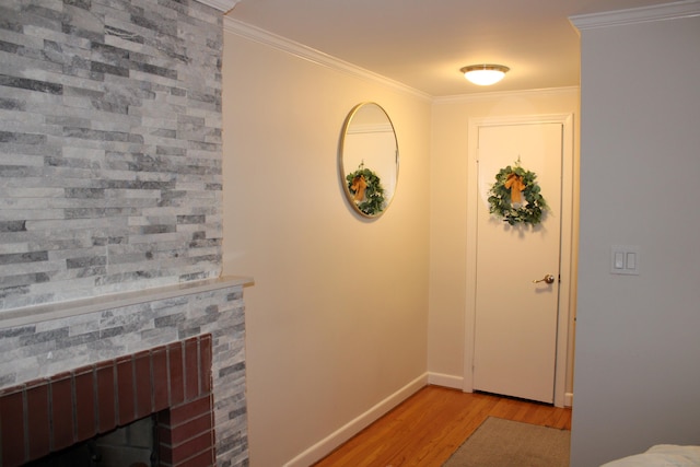 foyer entrance featuring a fireplace, crown molding, baseboards, and wood finished floors