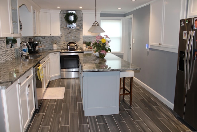 kitchen featuring a center island, a sink, wood finish floors, wall chimney exhaust hood, and appliances with stainless steel finishes