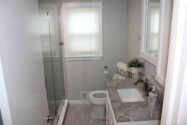 bathroom featuring toilet, a baseboard heating unit, vanity, visible vents, and a stall shower