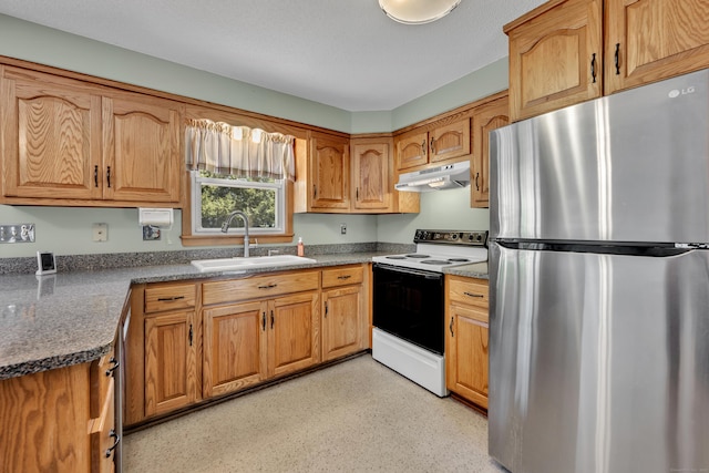 kitchen featuring a sink, brown cabinetry, electric stove, freestanding refrigerator, and under cabinet range hood