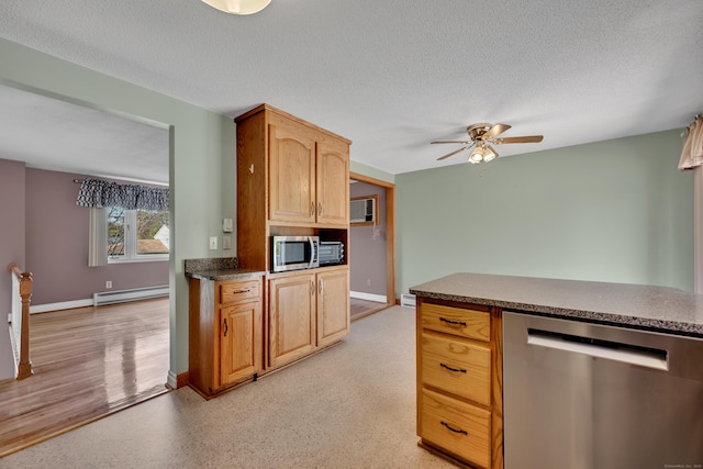 kitchen with dark countertops, ceiling fan, a textured ceiling, a baseboard heating unit, and appliances with stainless steel finishes