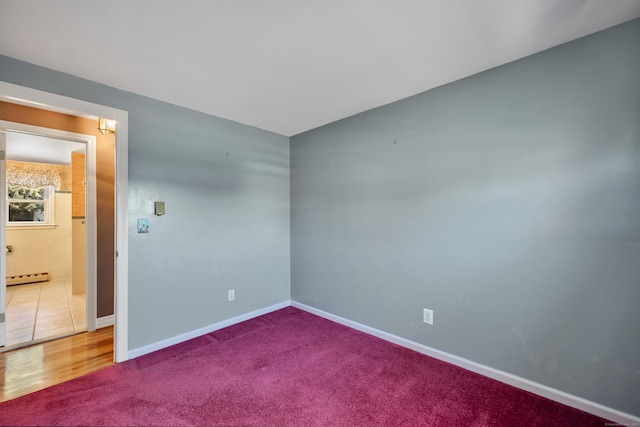 spare room with baseboards, carpet, and a baseboard heating unit