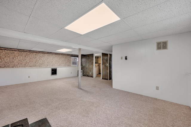 finished basement with visible vents, carpet flooring, a paneled ceiling, and washer / dryer