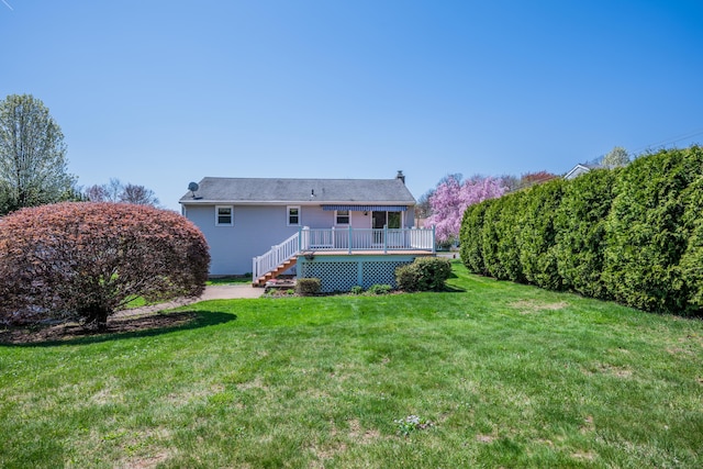 rear view of house featuring a wooden deck, a yard, and a chimney