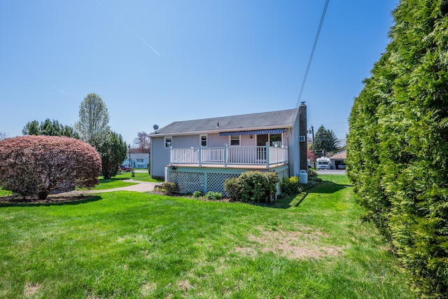 rear view of house featuring a yard, a deck, and a chimney