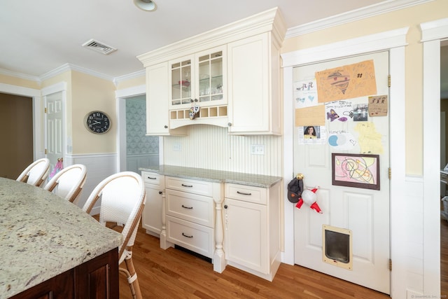 114 Cobbler Ln, Southbury, CT 06488 - kitchen with crown molding, light stone countertops, wood finished floors, visible vents, and glass insert cabinets