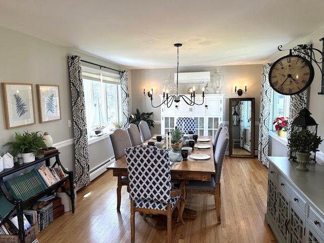 dining area featuring baseboard heating, an inviting chandelier, a wall mounted air conditioner, and light wood-style floors