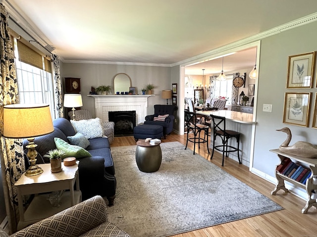 living area with a fireplace, wood finished floors, baseboards, and ornamental molding