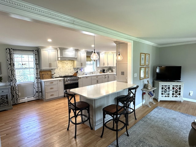 kitchen featuring a kitchen breakfast bar, light wood-style floors, gray cabinets, light countertops, and stainless steel gas range oven