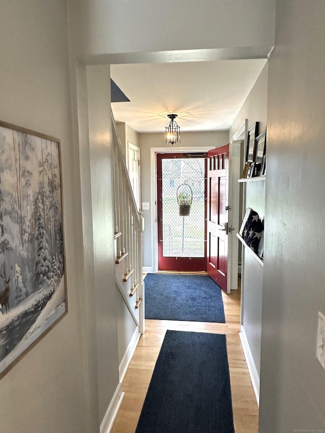 foyer featuring stairs, a notable chandelier, baseboards, and light wood-type flooring