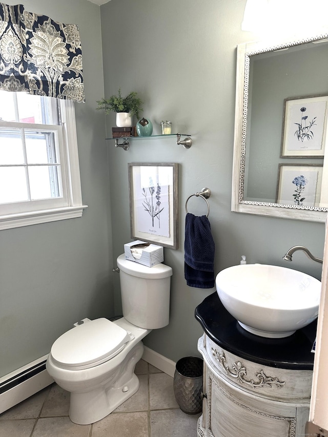 half bathroom featuring baseboard heating, toilet, vanity, baseboards, and tile patterned flooring