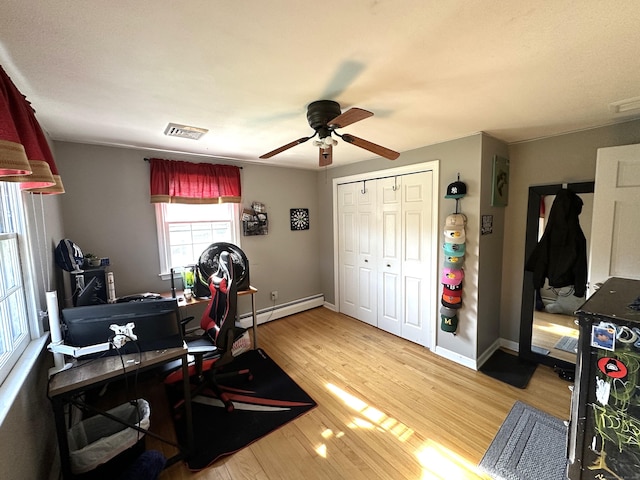 office featuring wood finished floors, visible vents, a ceiling fan, baseboards, and baseboard heating