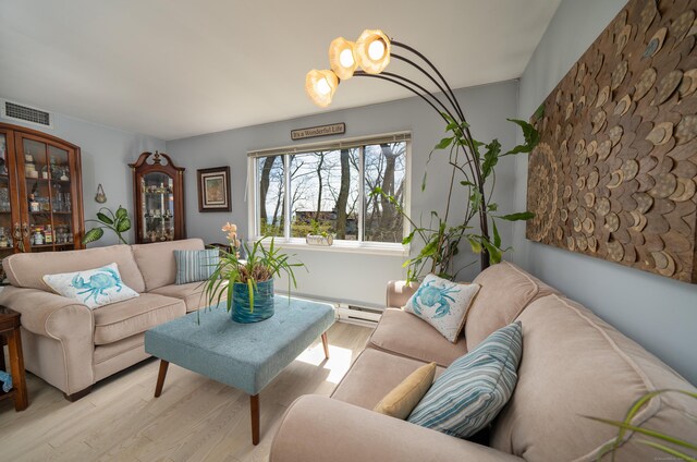 living room featuring baseboard heating, light wood-style flooring, and visible vents