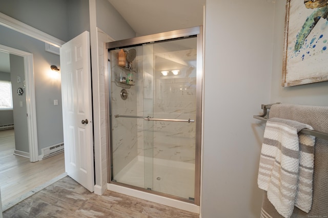 bathroom featuring a shower stall, baseboard heating, and wood finished floors