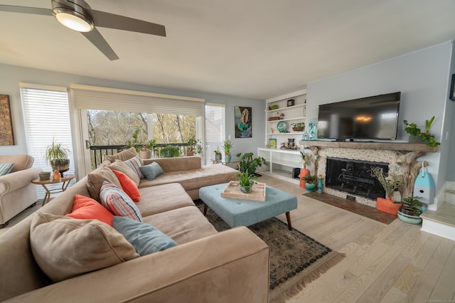 living area with a high end fireplace, a ceiling fan, and wood finished floors